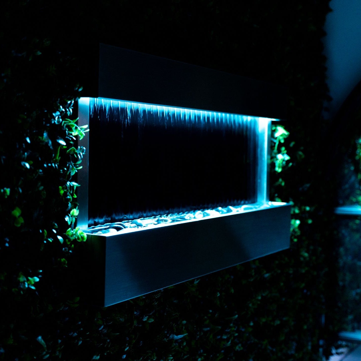 Modern wall-mounted water feature with blue LED lighting in a dark setting